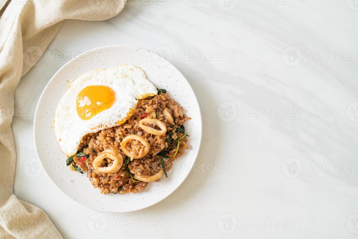 stekt ris med bläckfisk och basilika toppade stekt ägg i thailändsk stil foto