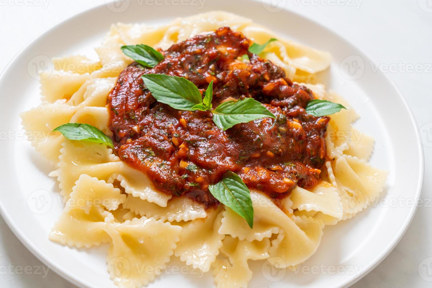 farfalle pasta med basilika och vitlök i tomatsås foto