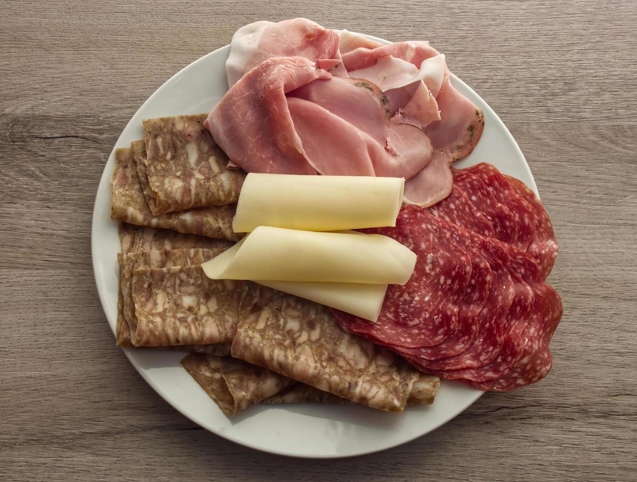 maträtt av olika italiensk salami. tallrik med diverse chark på träbakgrund foto