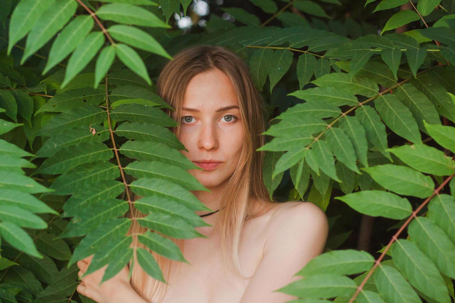 porträtt av vacker ung kvinna i gröna löv, blond söt dam i vårens buskar foto