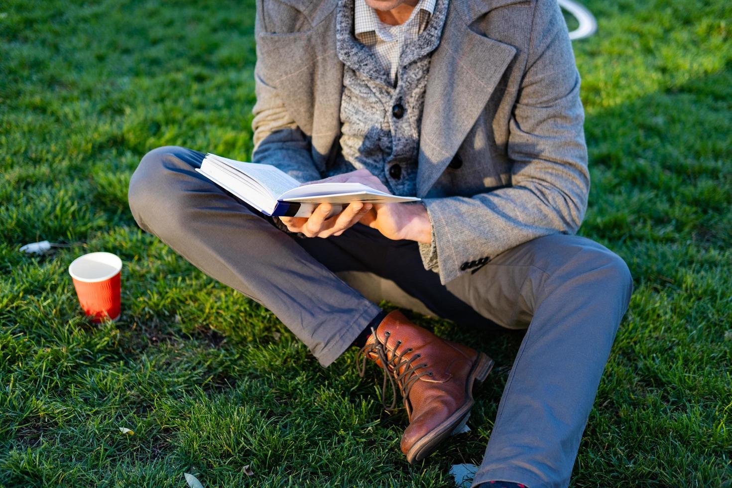 ung manlig hipster läsa bok i höst park foto