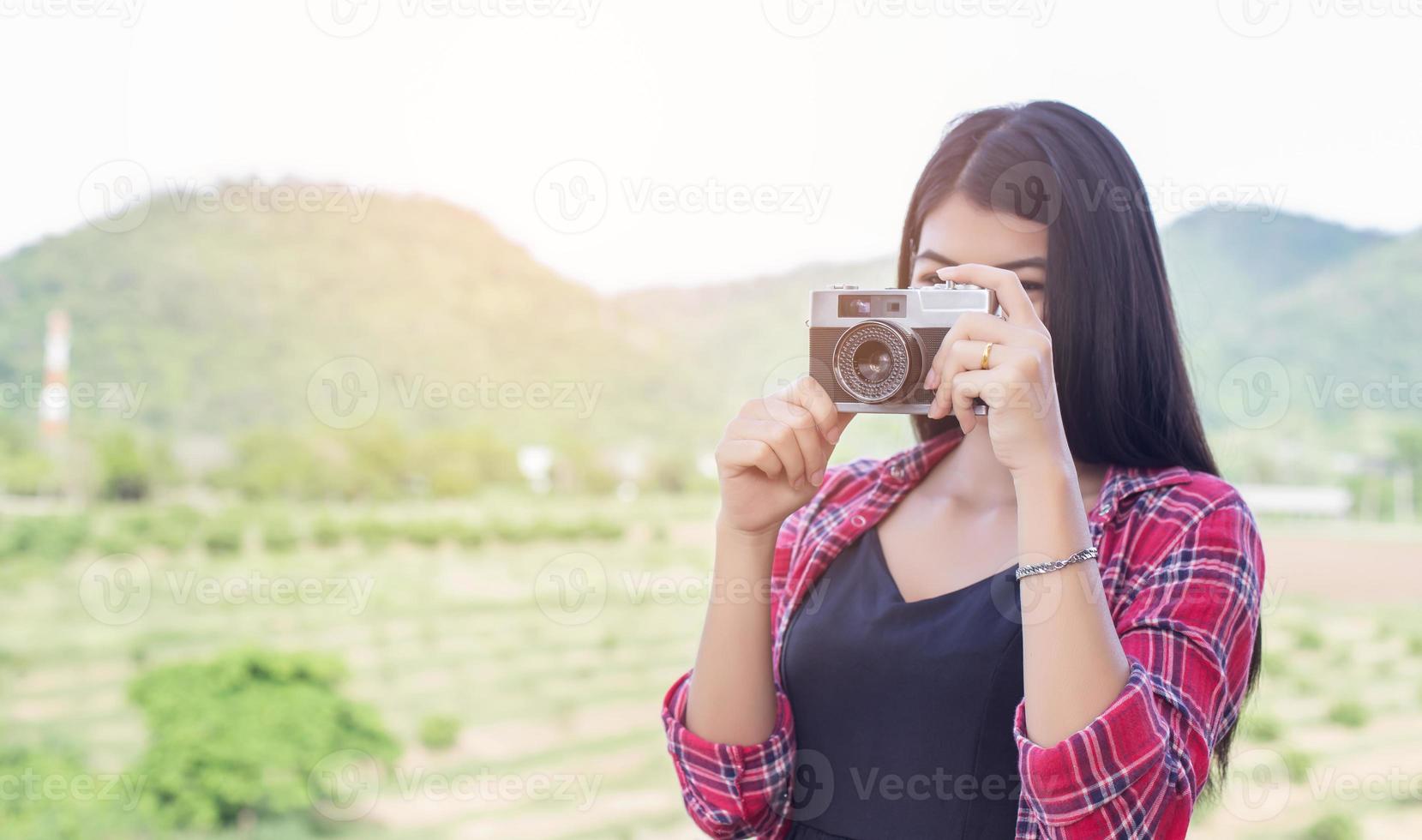 ung hipster kvinna fotograf som håller en vintage kamera. foto