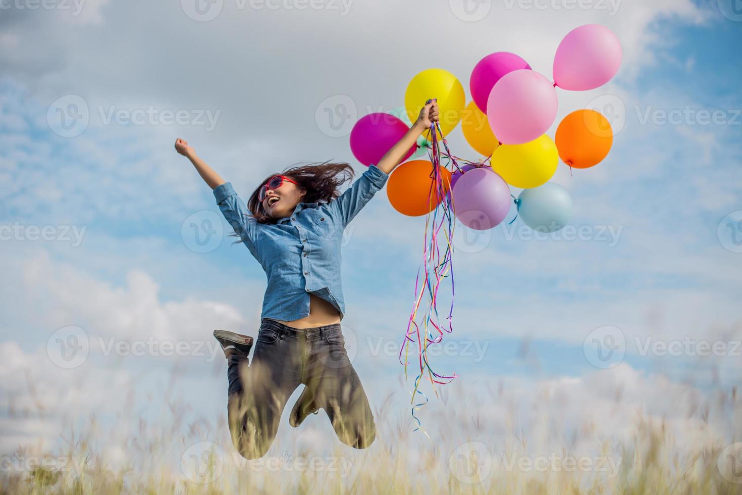 vacker flicka hoppar med ballonger på stranden foto