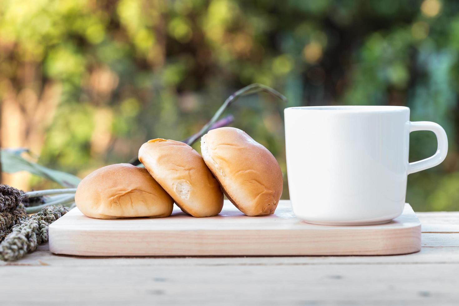 kaffekopp och bröd på trägolv foto