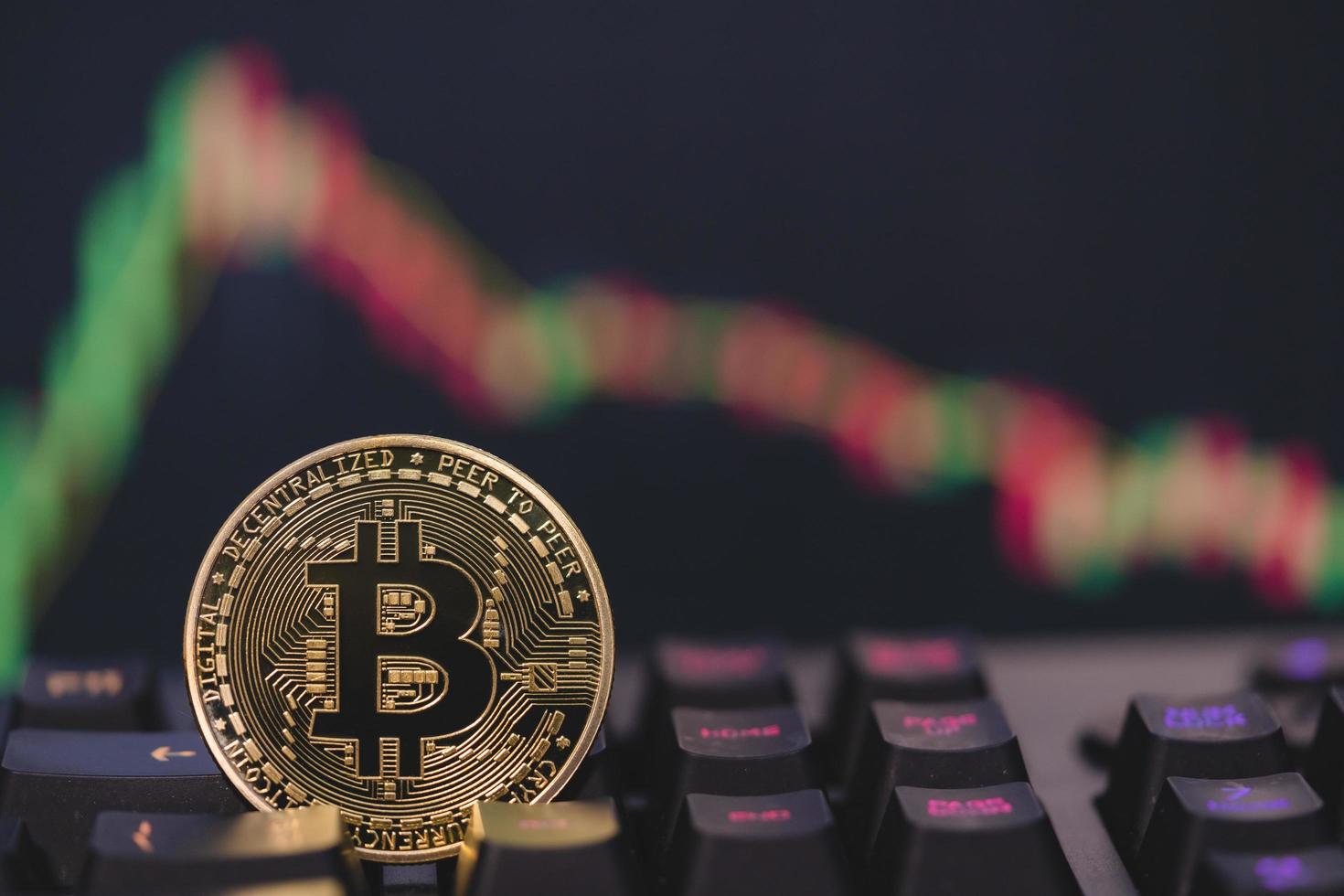 bitcoin btc-gruppen inkluderade kryptovaluta och aktiediagram ljusstake ned trend tappar aktier på datorns tangentbord. använda teknik kryptovaluta blockchain. fokus välj och oskärpa närbild mynt. foto