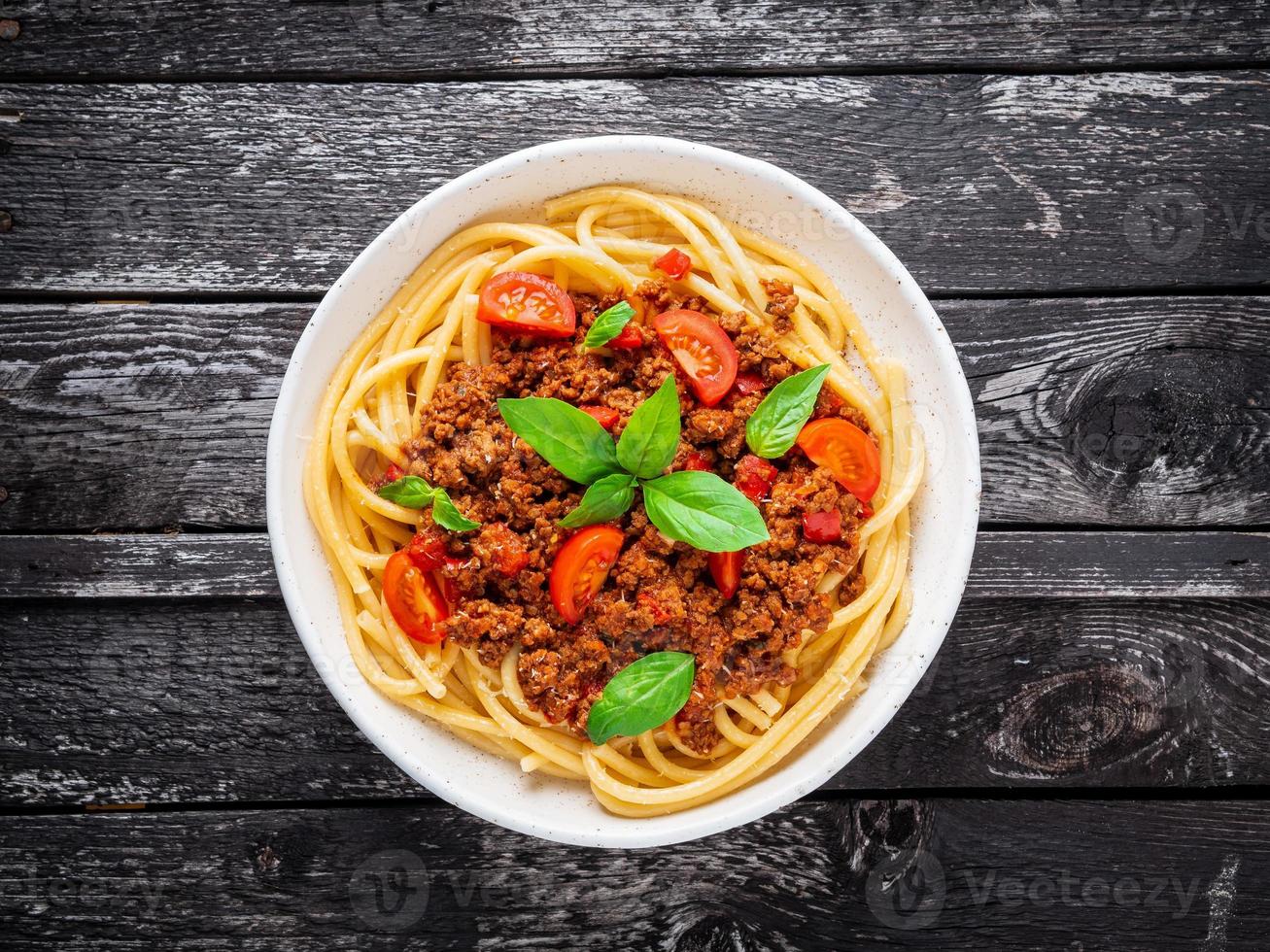 pasta bolognese med tomatsås, malet nötkött, basilikablad på bakgrunden foto