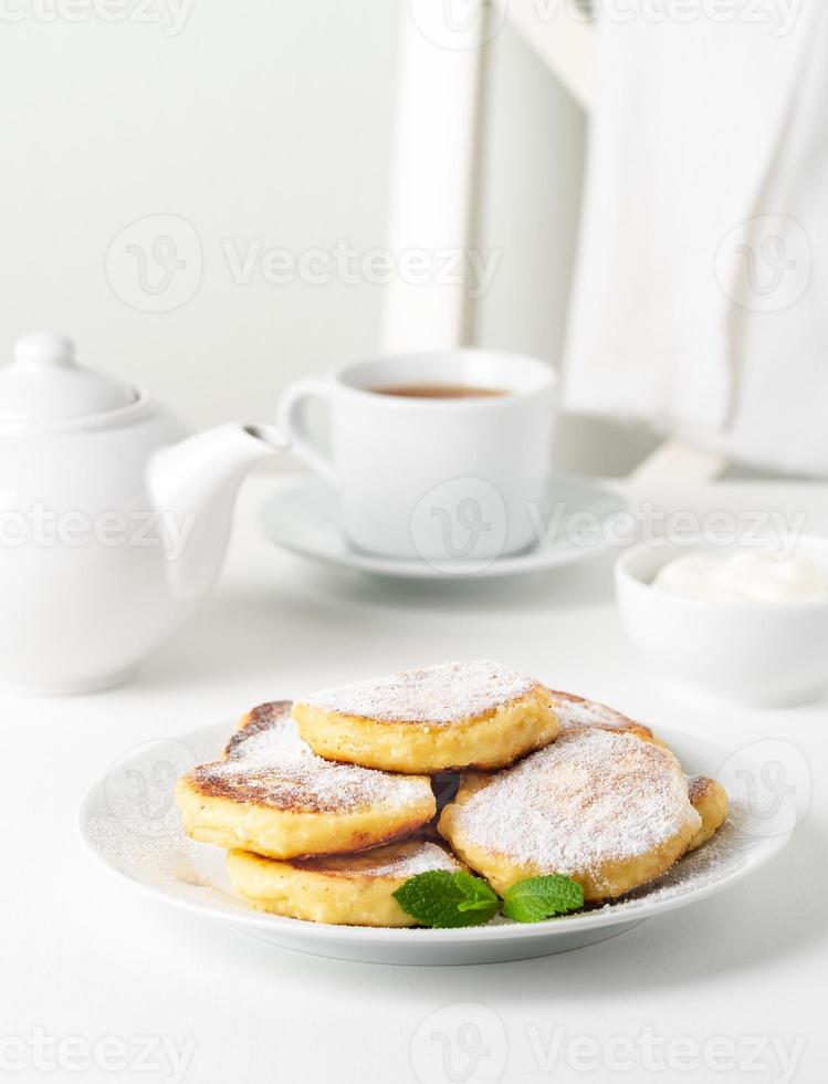 stekta ostkakor, sötostpannkakor på vit platta på vit bakgrund. hem teparty foto