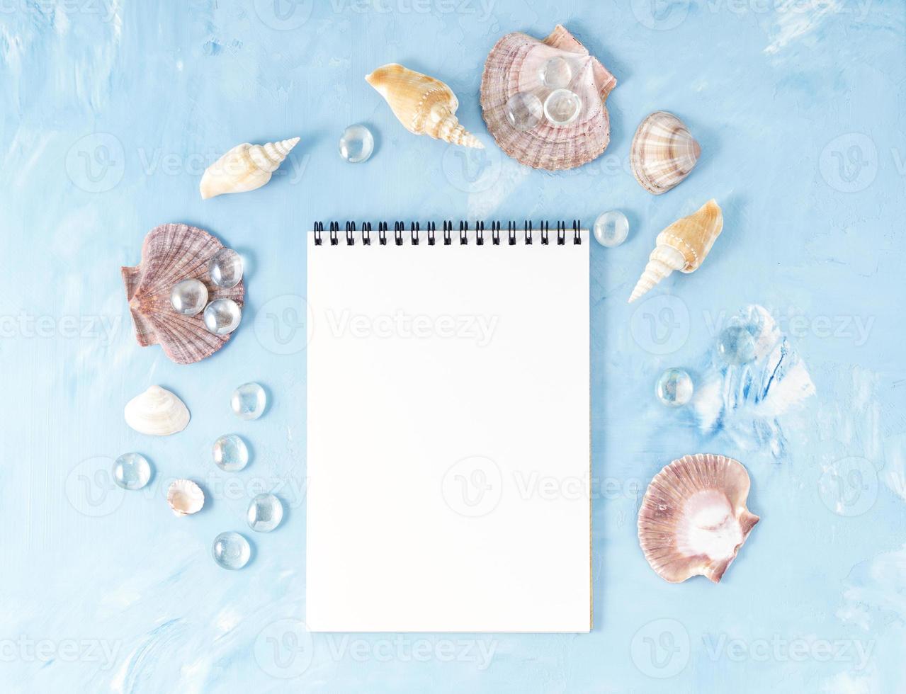 mock up med ram av snäckskal, anteckningsblock på blå sten bakgrund, kopia utrymme. sommar koncept av semester till sjöss foto