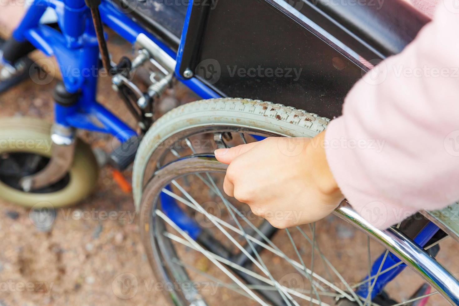 hand handikapp kvinna i rullstol hjul på väg i sjukhus park väntar på patienttjänster. oigenkännlig förlamad tjej i invalid stol för funktionshindrade utomhus. rehabiliteringskoncept. foto