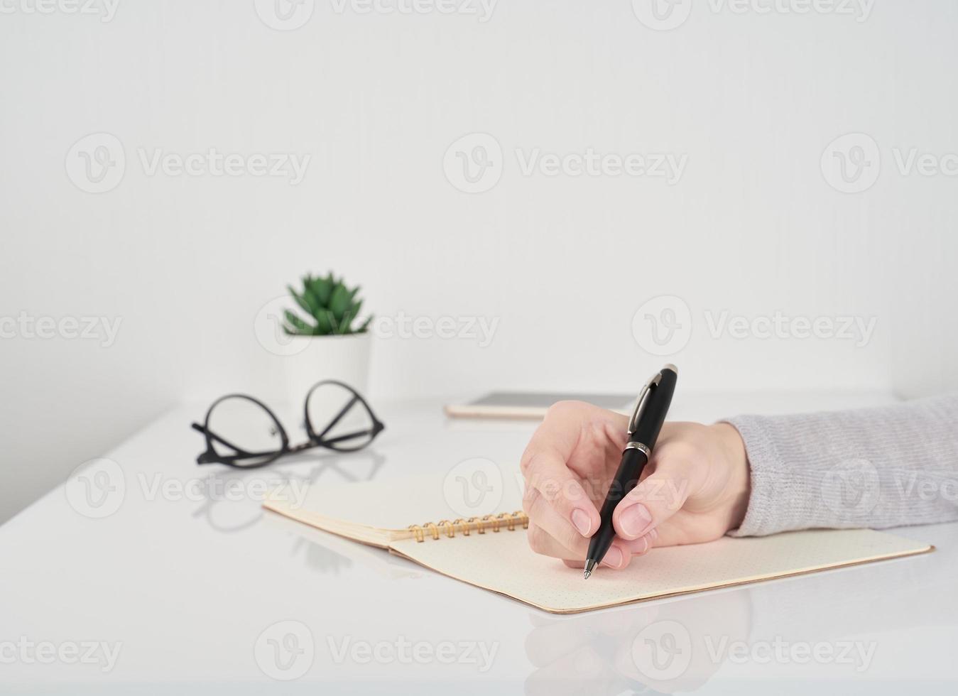 kvinna skriver i anteckningsbok, kontorsarbete koncept på vit vägg bakgrund foto