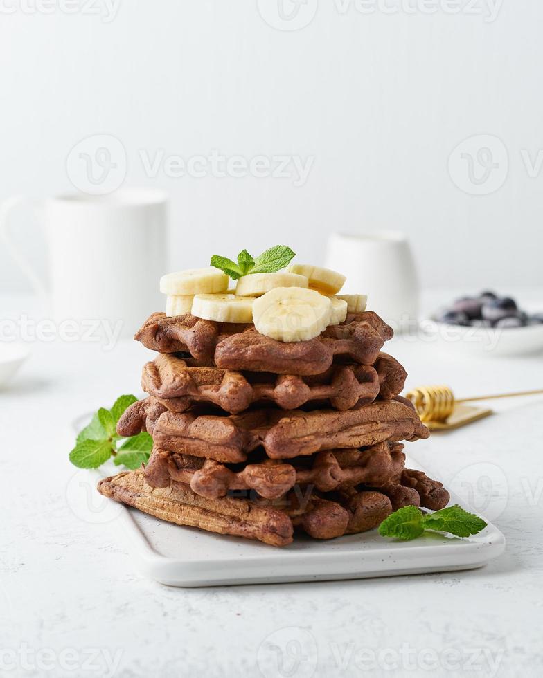 choklad bananvåfflor med lönnsirap på vitt bord, sidovy, vertikal. söt brunch foto