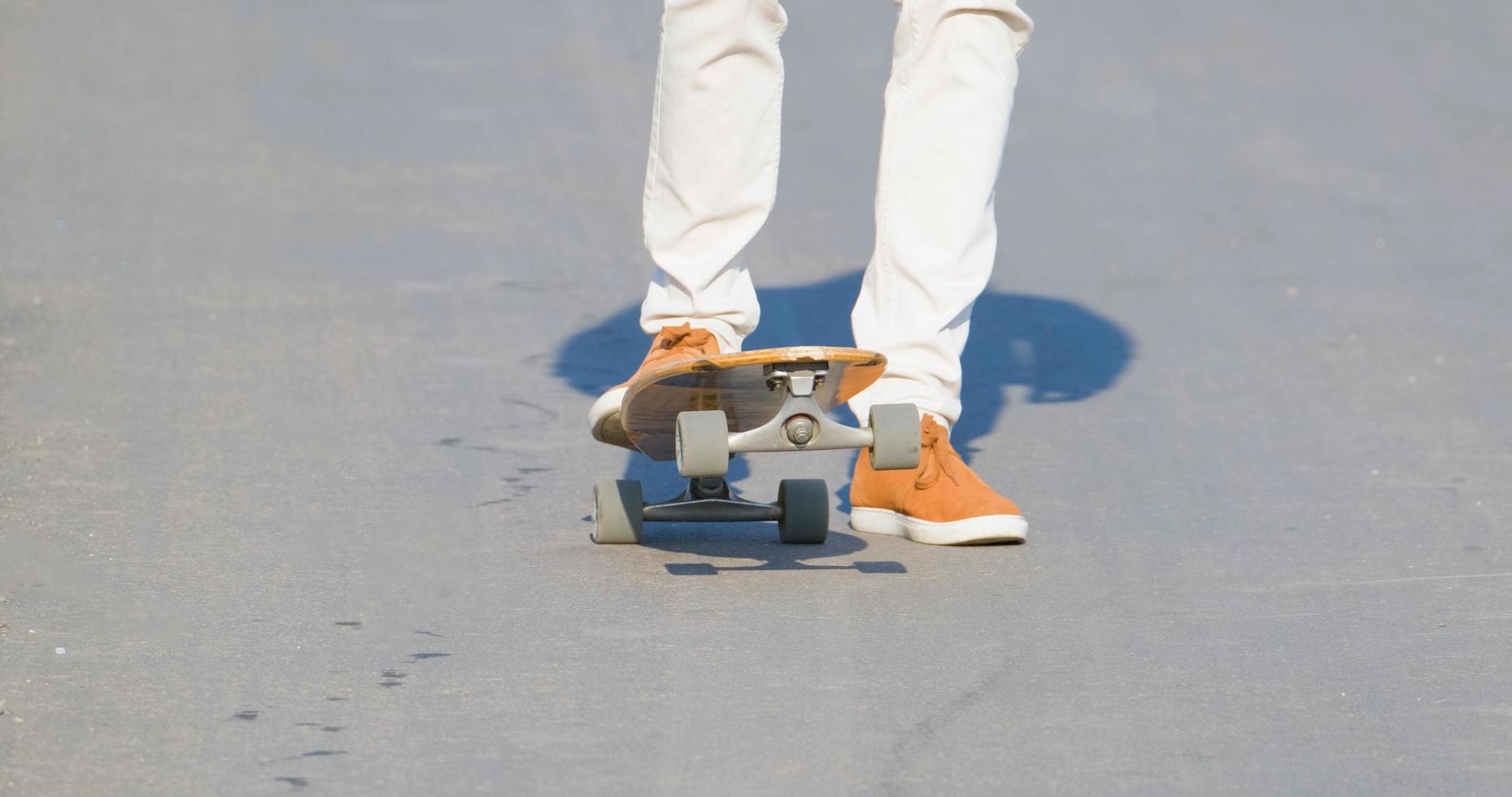 ung man rida på longboard skateboard på landsvägen i solig dag foto