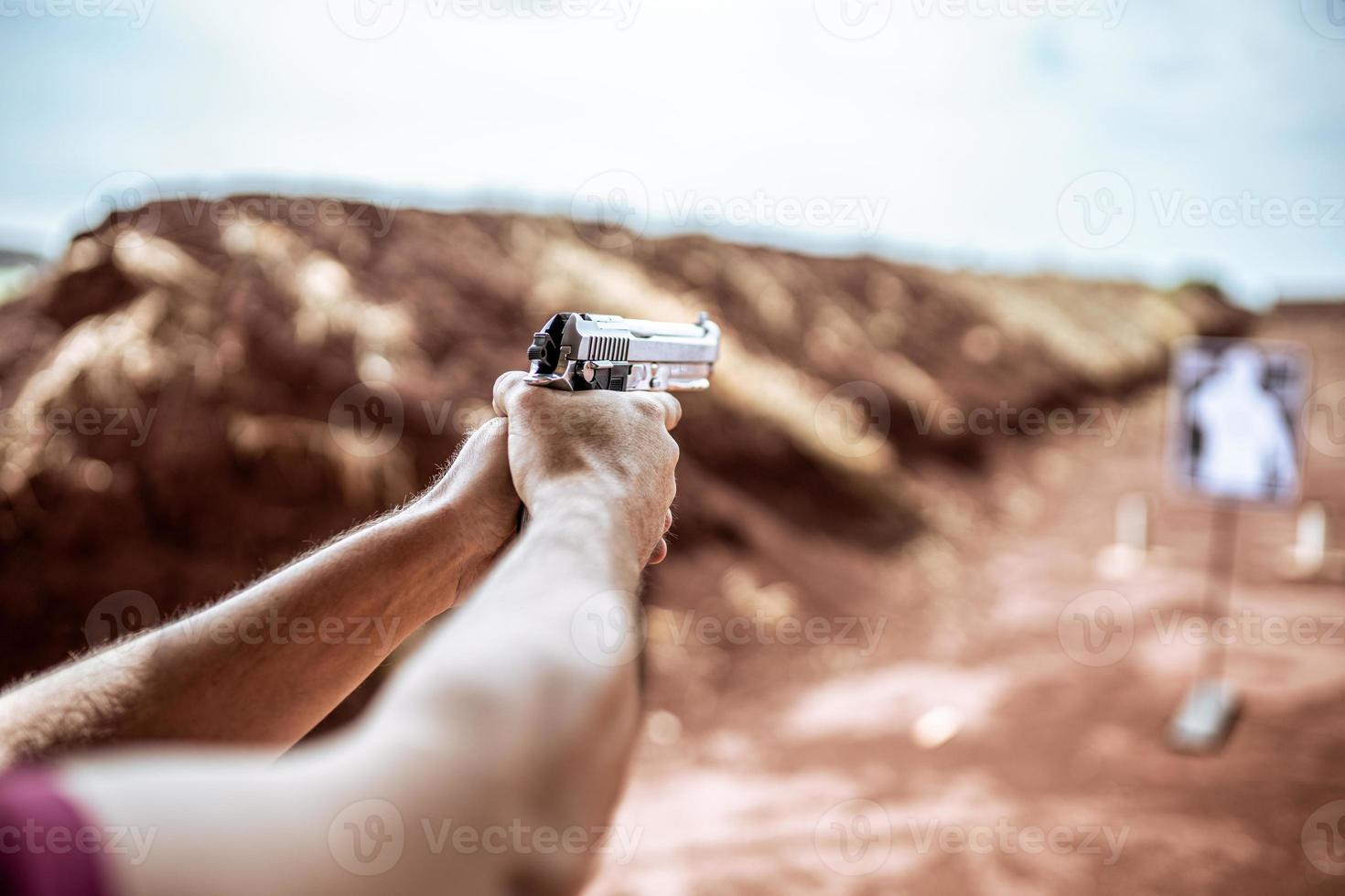 detaljvy av skytten som håller pistol och tränar taktiskt skytte, fokus på pistol. skjutbana. foto