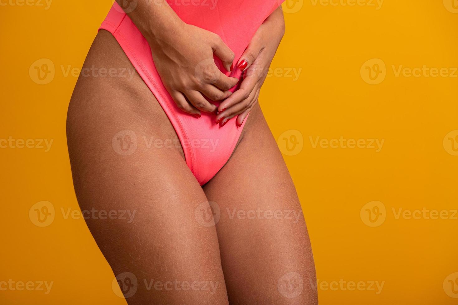 kvinna som lider av magont och klagar. mensvärk. ung vacker kvinna har ont i magen. på gul bakgrund. foto