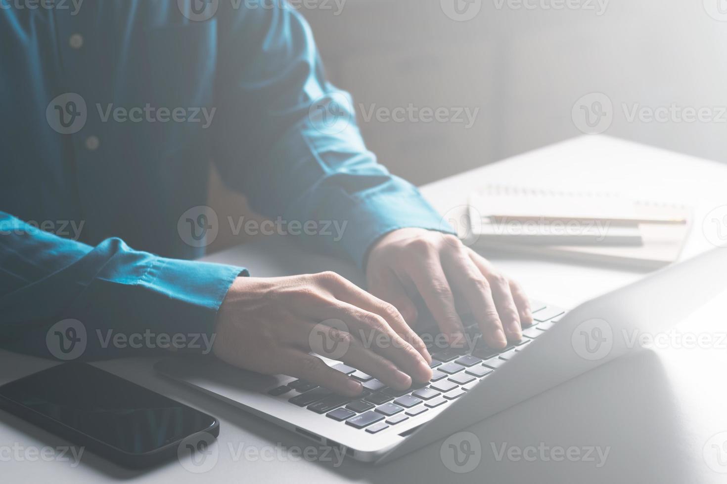 affärsmän arbetar på datorer och skriver på anteckningsblock med en penna för att beräkna bokslutet inom företaget. foto