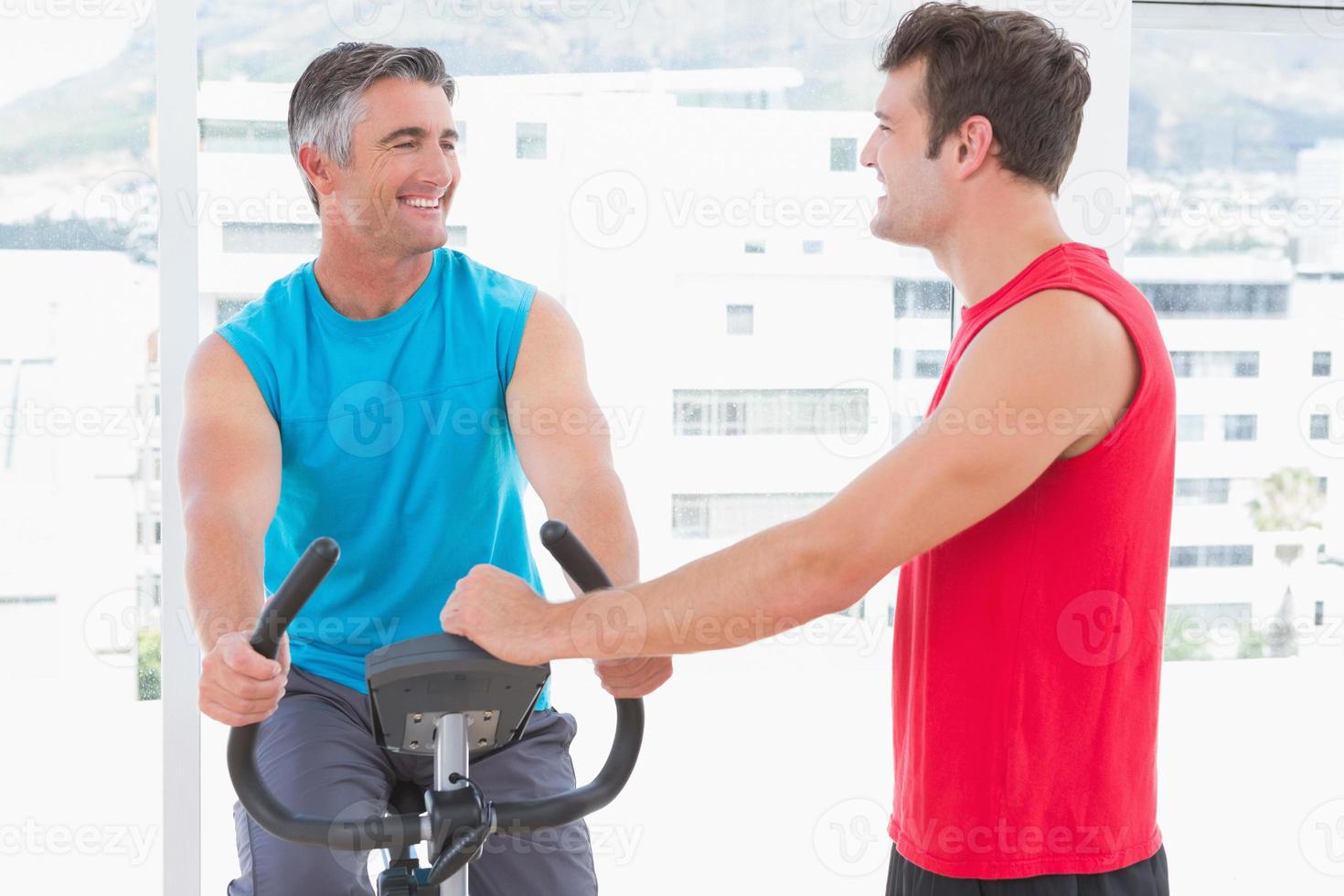 tränare med mannen på motionscykeln foto