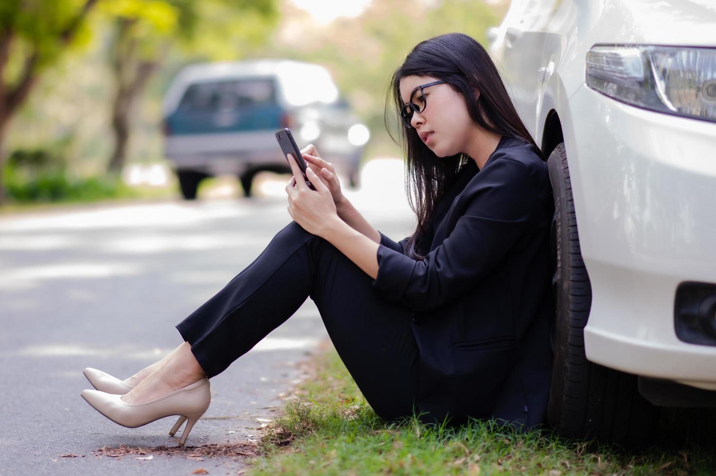 en ung asiatisk kvinna ringer sin servicetekniker för att laga en trasig bil vid sidan av vägen foto