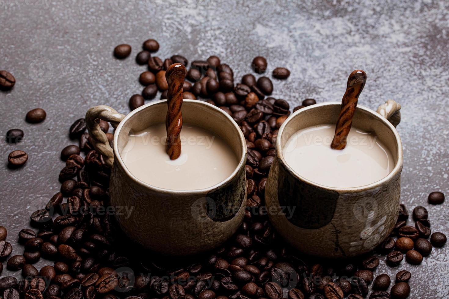 två muggar kaffe med kaffebönor på en mörk bakgrund. foto