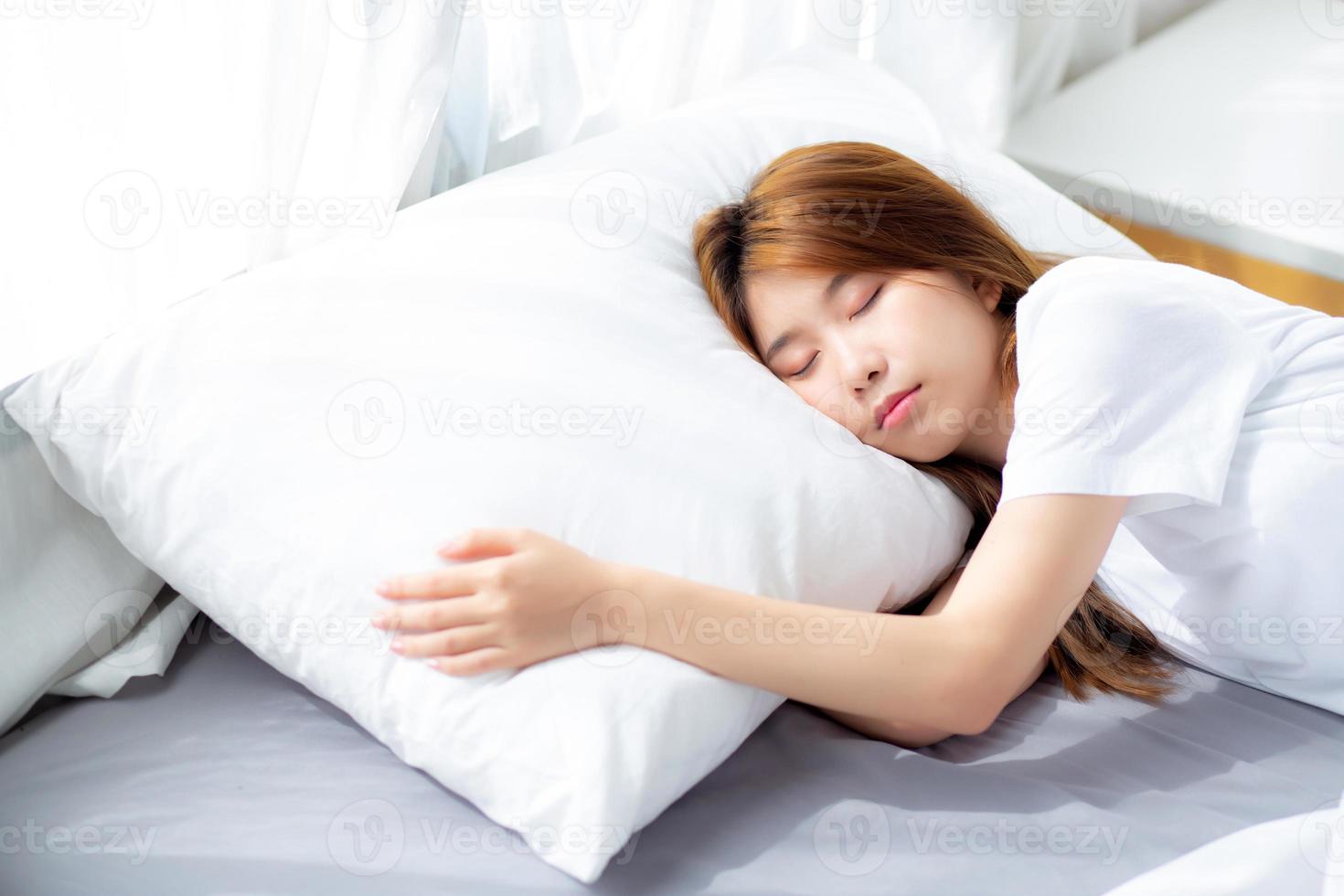 porträtt av vacker asiatisk ung kvinna sover liggande i sängen med huvudet på kudden bekväm och nöjd med fritid, tjej med relax för hälsa och livsstilskoncept. foto