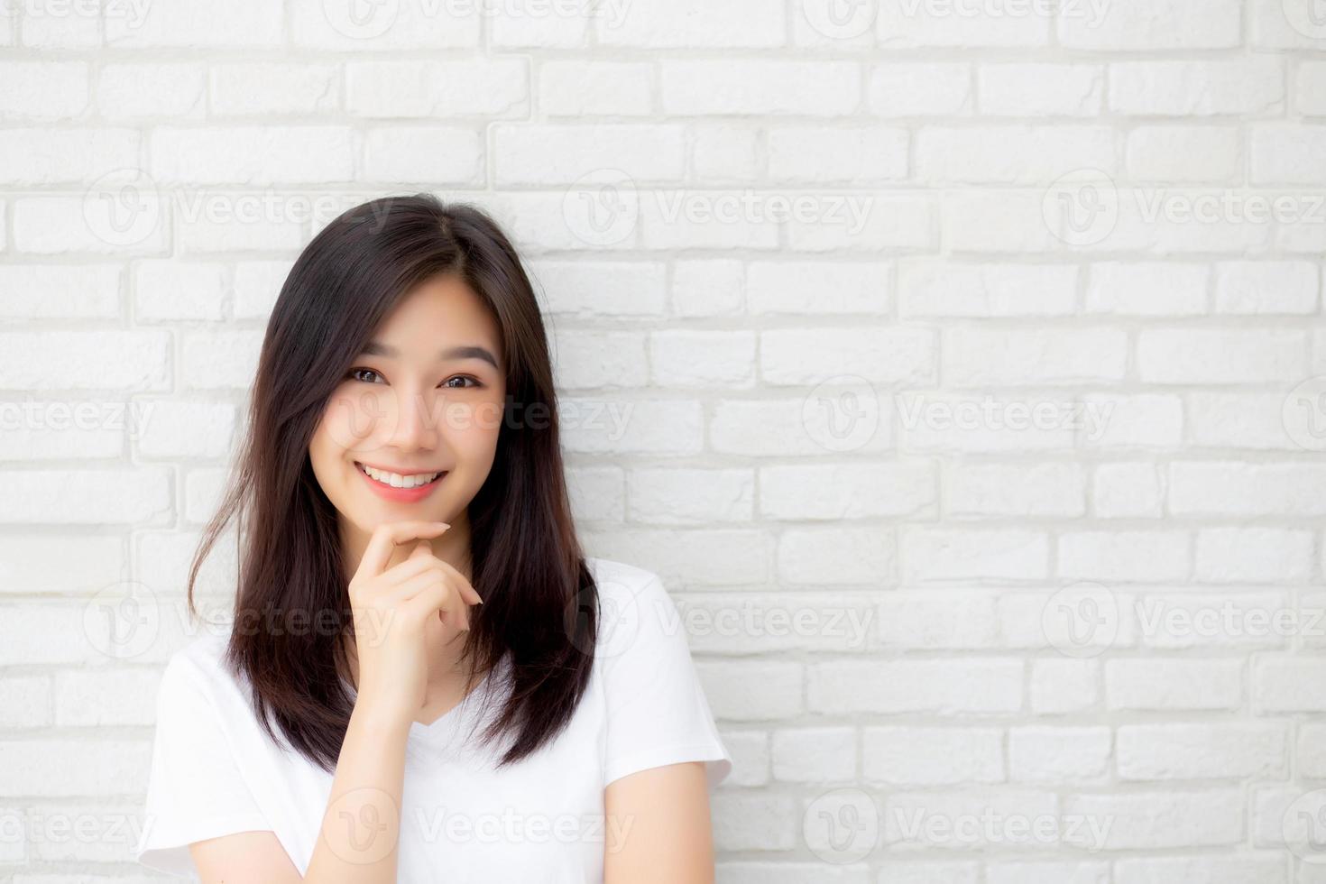 porträtt av vacker ung asiatisk kvinna lycka stående på grå cement textur grunge vägg tegel bakgrund, affärskvinna är ett leende på betong, affärsmän koncept. foto