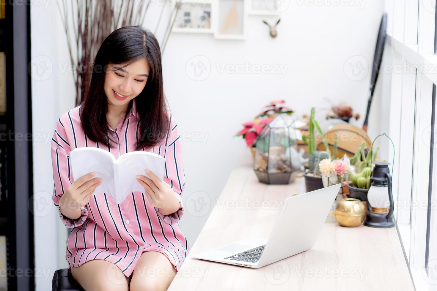 vacker av porträtt ung asiatisk kvinna koppla av sittande läsa bok i vardagsrummet hemma, flicka studera litteratur, utbildning och llifestyle koncept. foto