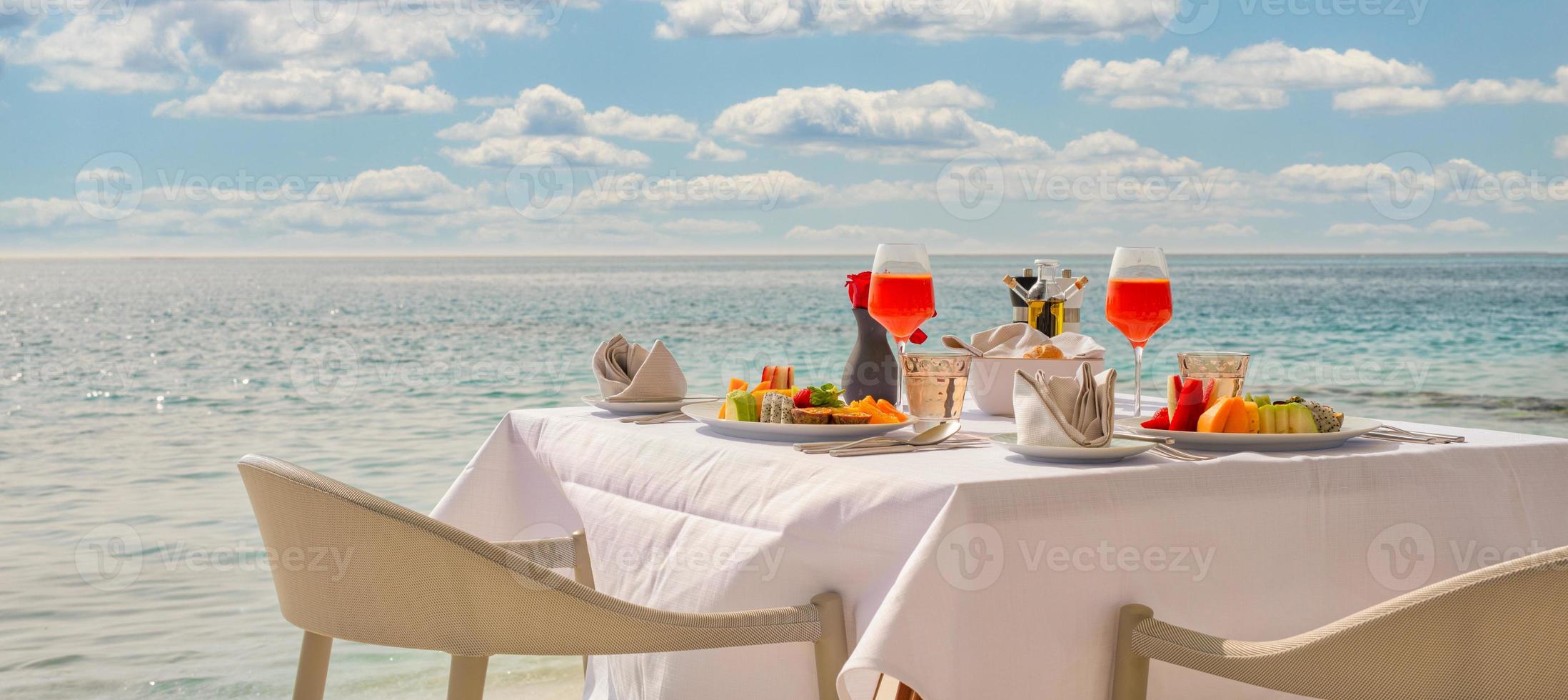lyxig frukostmat på vitt bord, med vacker tropisk havsutsiktbakgrund, morgontids sommarlov och romantiskt semesterkoncept, lyxresor och livsstil foto