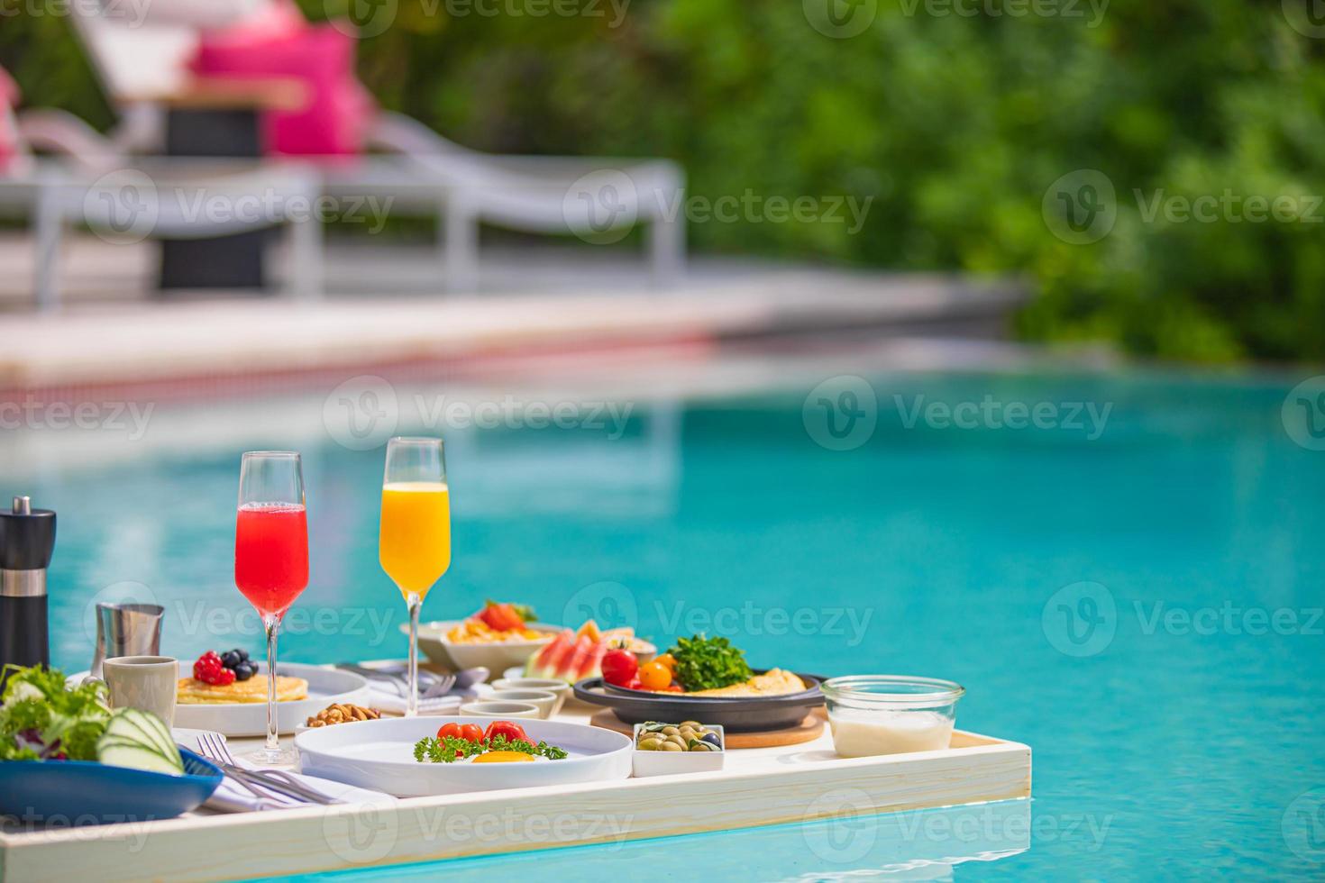 frukost i poolen, flytande frukost i lyxig tropisk resort. bord avkopplande på lugnt poolvatten, hälsosam frukost och fruktfat vid resortens pool. tropisk strand lyx livsstil foto