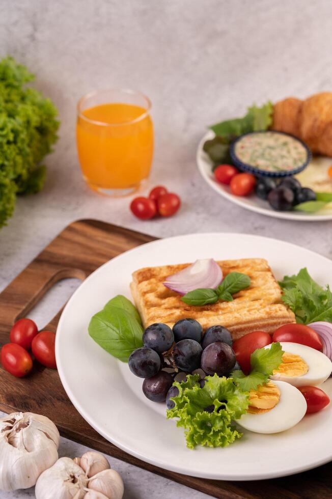 Frukosten består av bröd, kokta ägg, svart druvsalladsdressing, tomater. foto