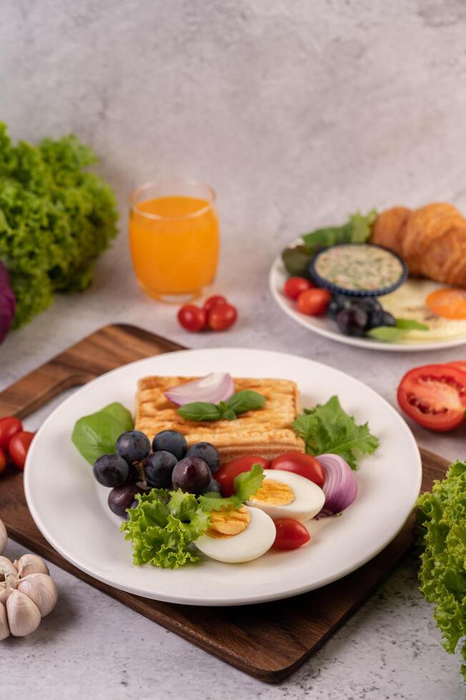 Frukosten består av bröd, kokta ägg, svart druvsalladsdressing, tomater. foto