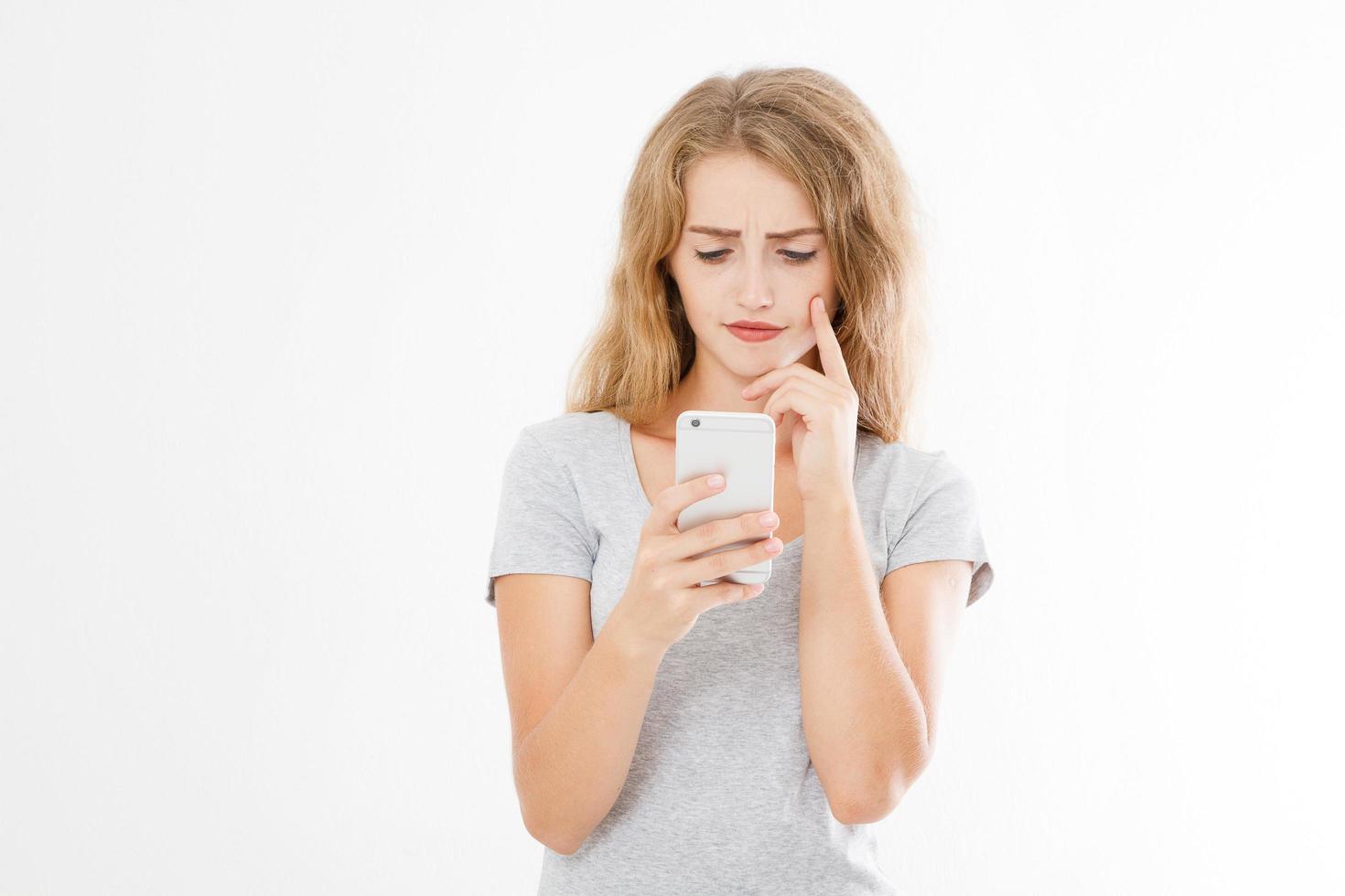 ung vacker kvinna i t-shirt med sin smartphone isolerad på vit bakgrund. sexig blond tjej chattar med en vän eller handlar online. kopieringsutrymme foto