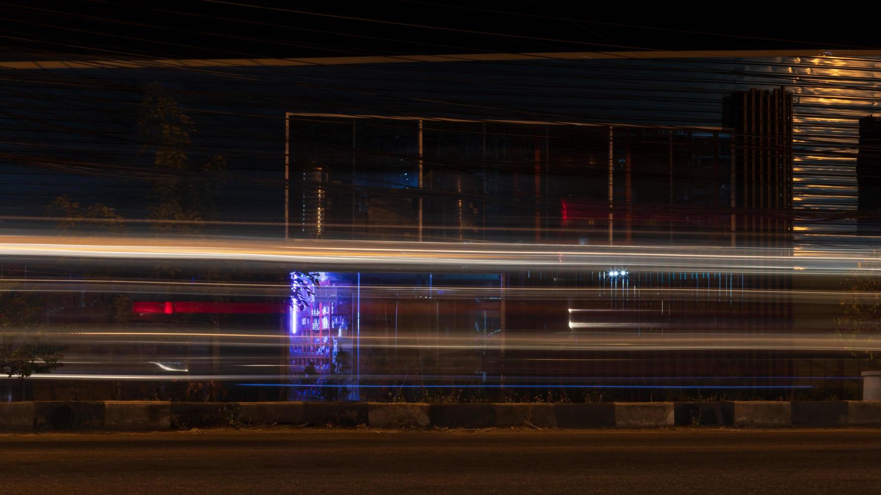 ljusa linjer av bilstrålkastare nära nattbyggnader. foto