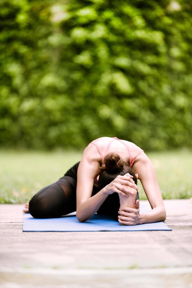 asiatiska kvinnors meditation och stretching slappnar av sina muskler genom att göra yoga i trädgården foto