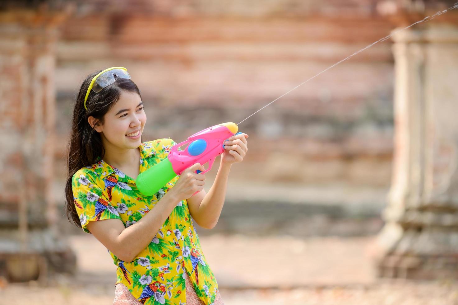 vackra asiatiska kvinnor håller plastvattenpistoler vid ett gammalt tempel under songkran, den vackraste och roligaste vattenfestivalen i thailand foto