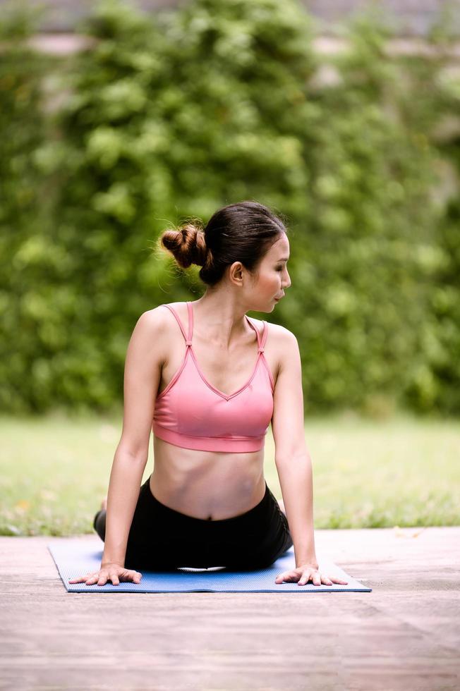 asiatiska kvinnors meditation och stretching slappnar av sina muskler genom att göra yoga i trädgården foto