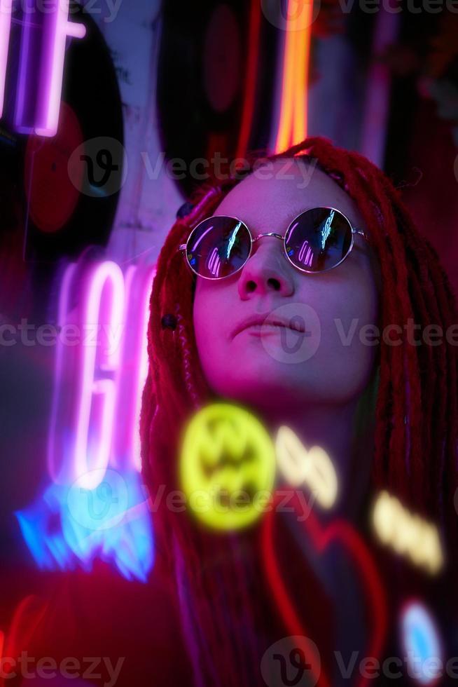 flicka i neonljus, vacker kvinna i solglasögon, med rosa hår, med dreadlocks pigtails foto