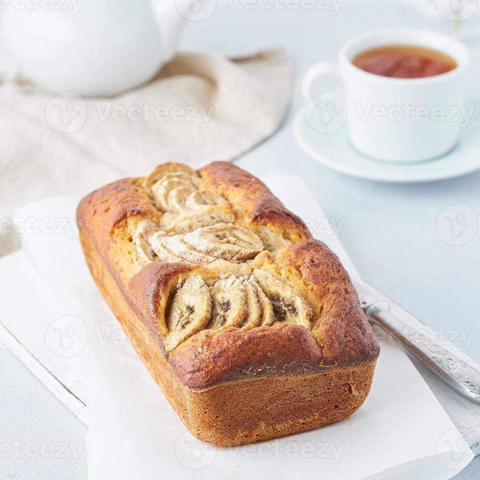 bananbröd, tårta med banan, sidovy. morgonfrukosten med te på ljusgrå bakgrund foto