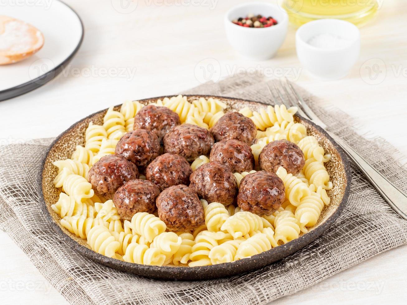 Svenska köttbullar med fusillipasta på vitt träbord, sidovy foto