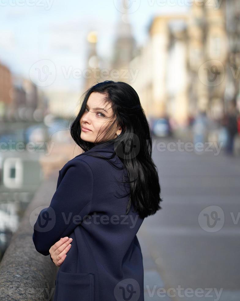 porträtt f vacker intelligent brunett som går nerför gatan i Saint-Petersburg i stadens centrum. charmig eftertänksam kvinna med långt mörkt hår vandrar ensam, nedsänkt i tankar foto