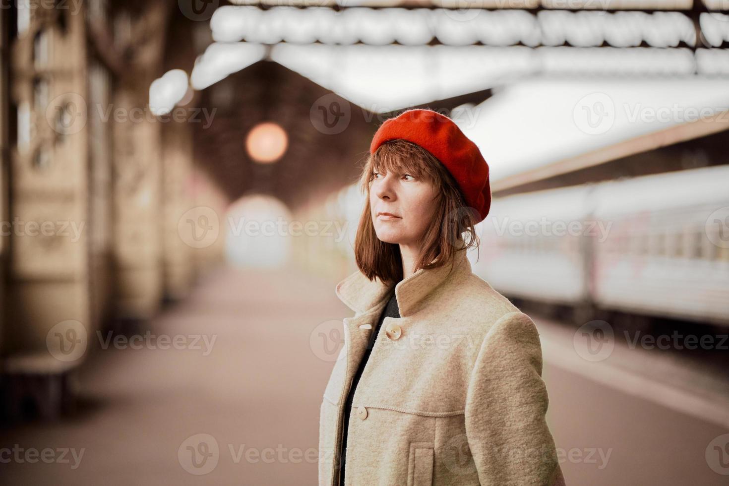 närbild porträtt av vacker kvinna, leende och väntar på tåget på järnvägsstationen. flicka reser lätt foto