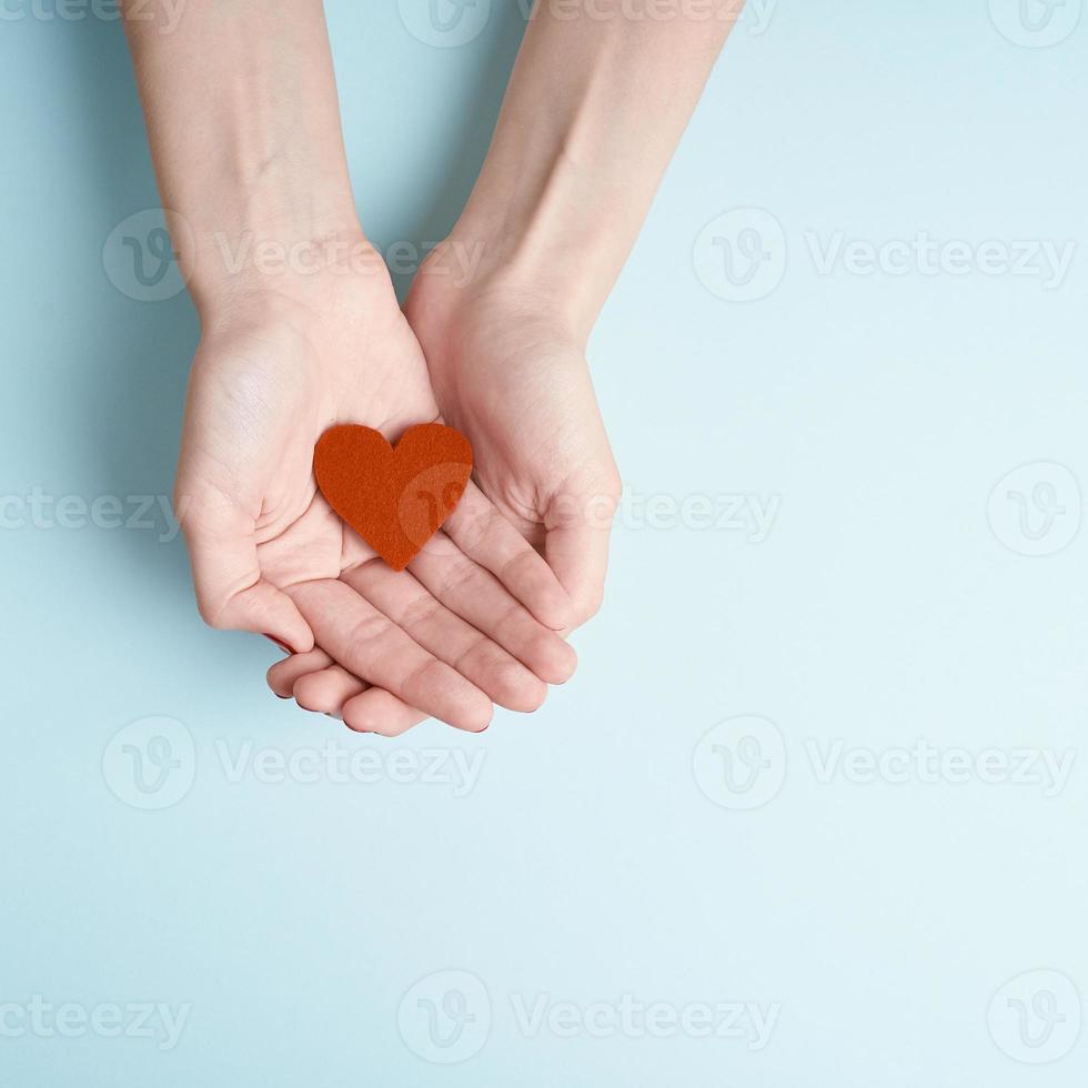 person som håller rött hjärta i händerna, donera och familjeförsäkringskoncept, på akvamarinbakgrund foto