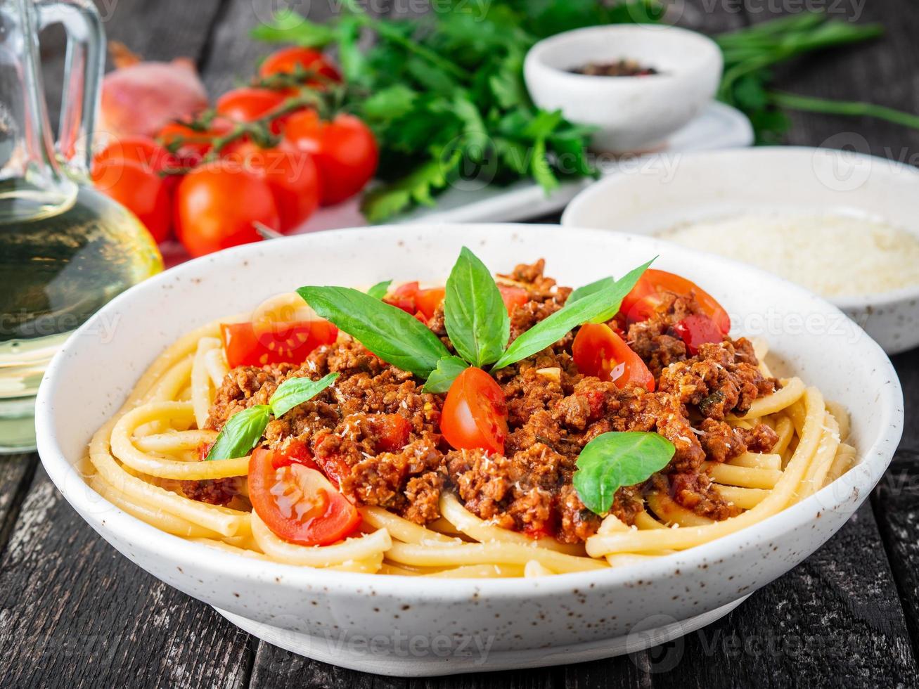 pasta bolognese med tomatsås, malet nötkött, basilikablad på bakgrunden foto