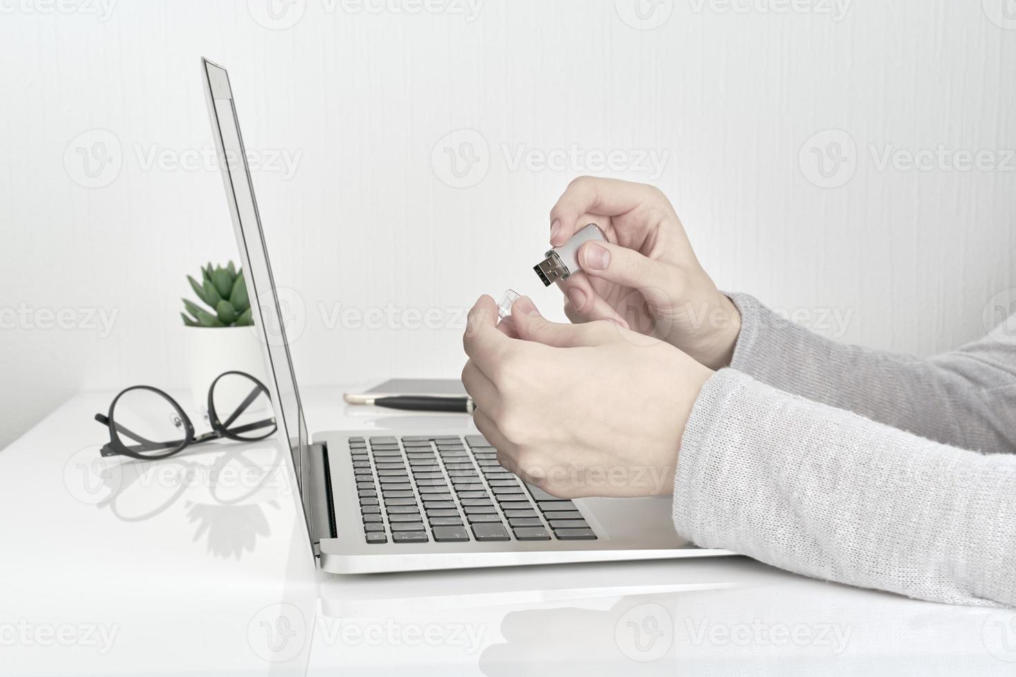 person som öppnar usb-blixt bredvid laptop, kontorsarbete koncept på vit väggbakgrund foto