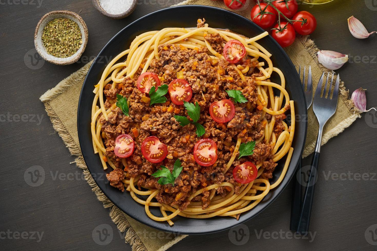 pasta bolognese bucatini med köttfärs och tomater, mörk trä bakgrund, ovanifrån foto