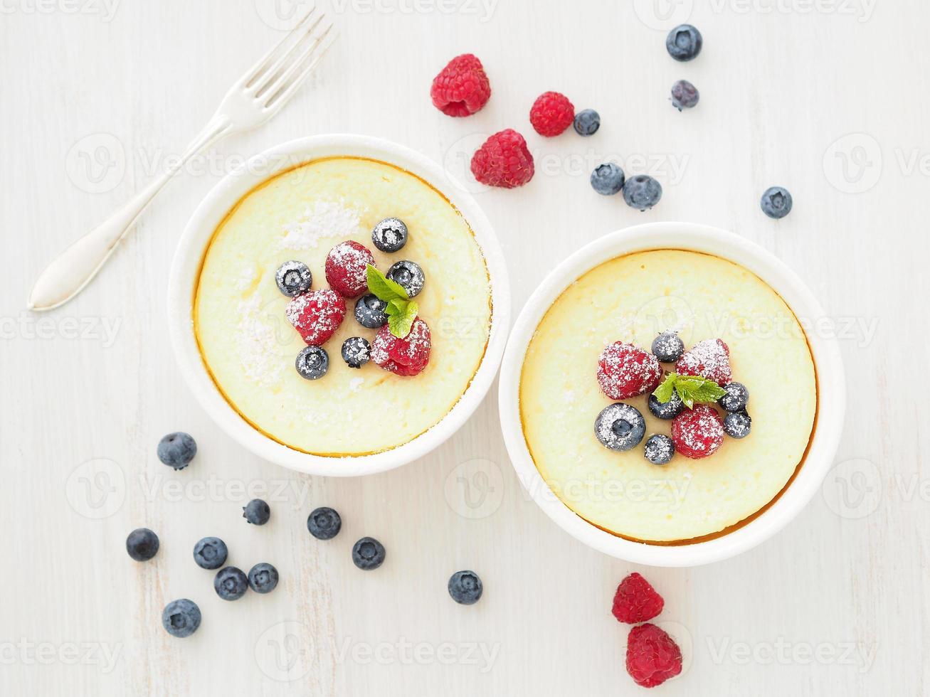 cheesecake dekorerad med hallon, blåbär och mynta i två ramekin, läcker dessert foto