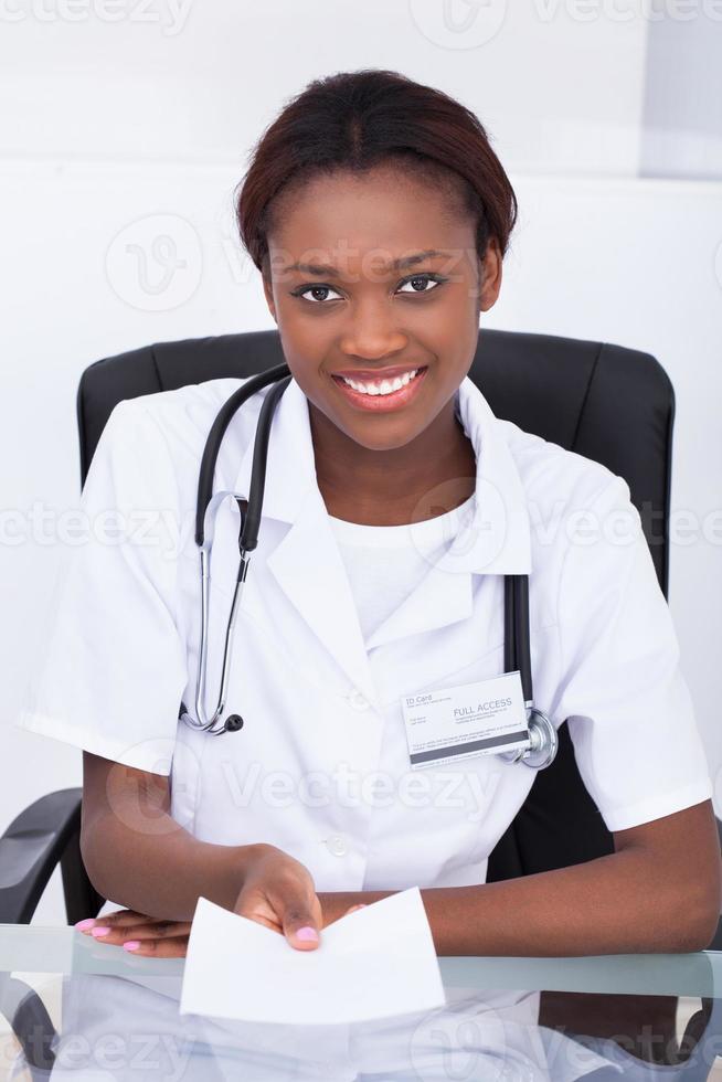 kvinnlig läkare som ger receptpapper vid skrivbordet foto