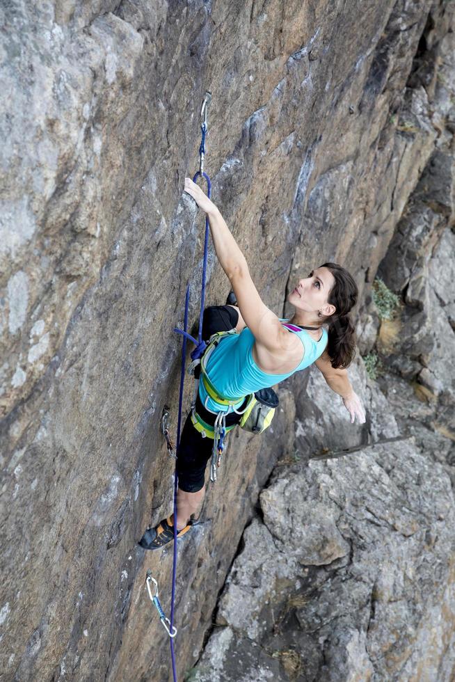 kvinnlig bergsklättrare som hänger över avgrunden foto
