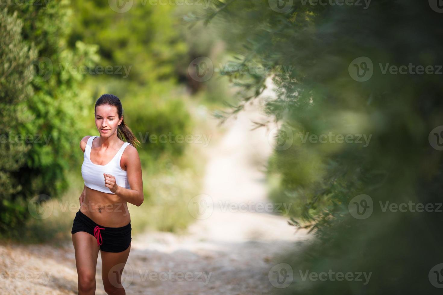 vacker ung kvinnlig löpare på en skogsstig foto