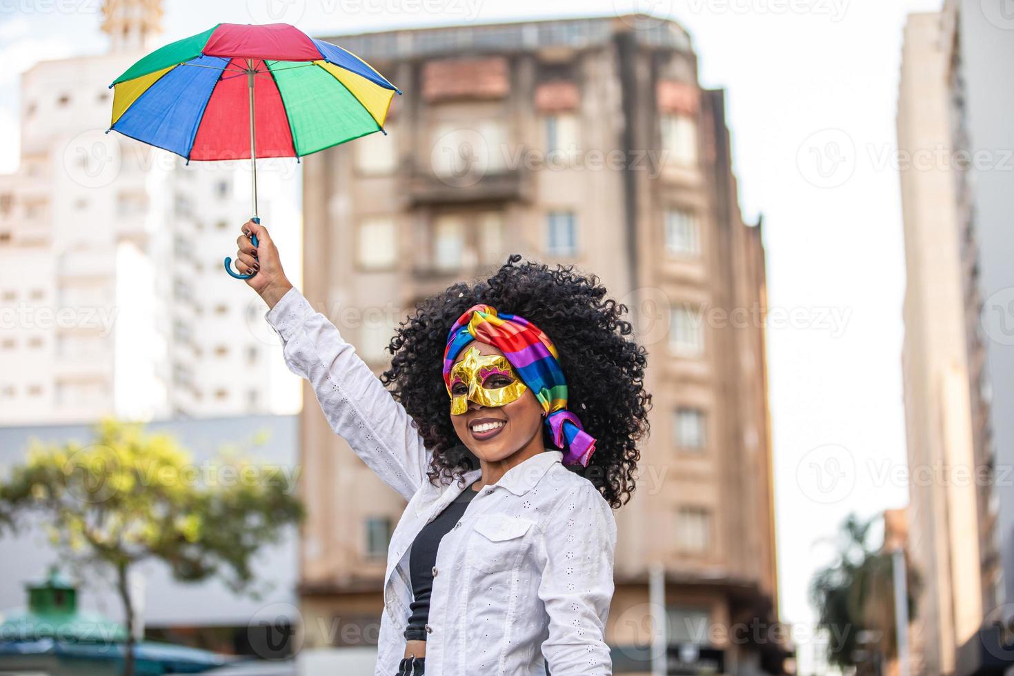 ung lockigt hår kvinna firar den brasilianska karnevalsfesten med frevo paraply på gatan. foto