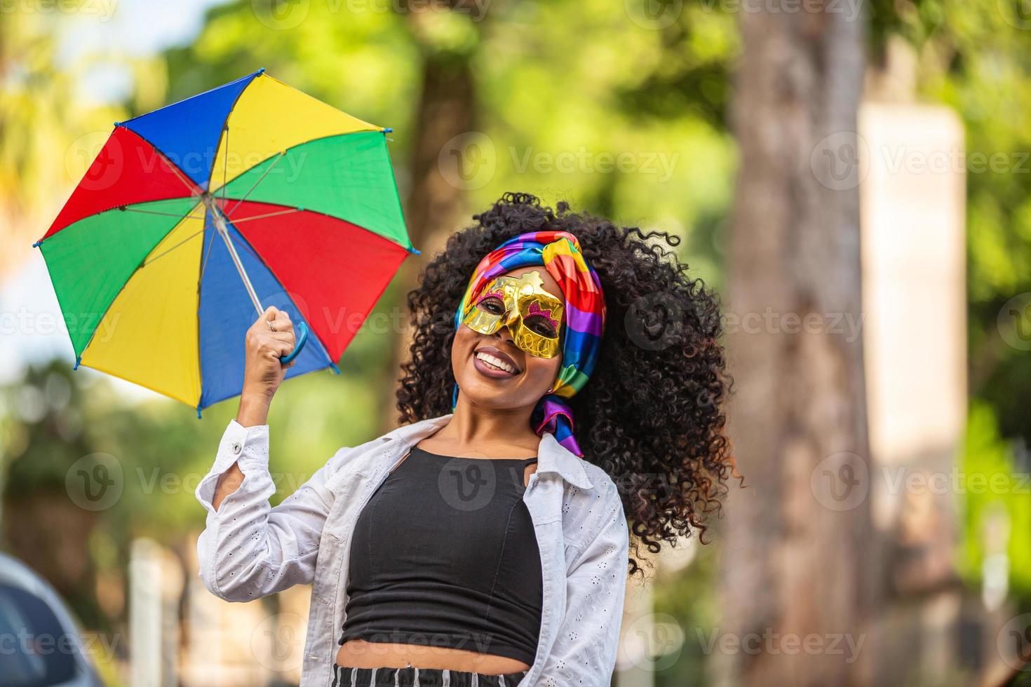 ung lockigt hår kvinna firar den brasilianska karnevalsfesten med frevo paraply på gatan. foto