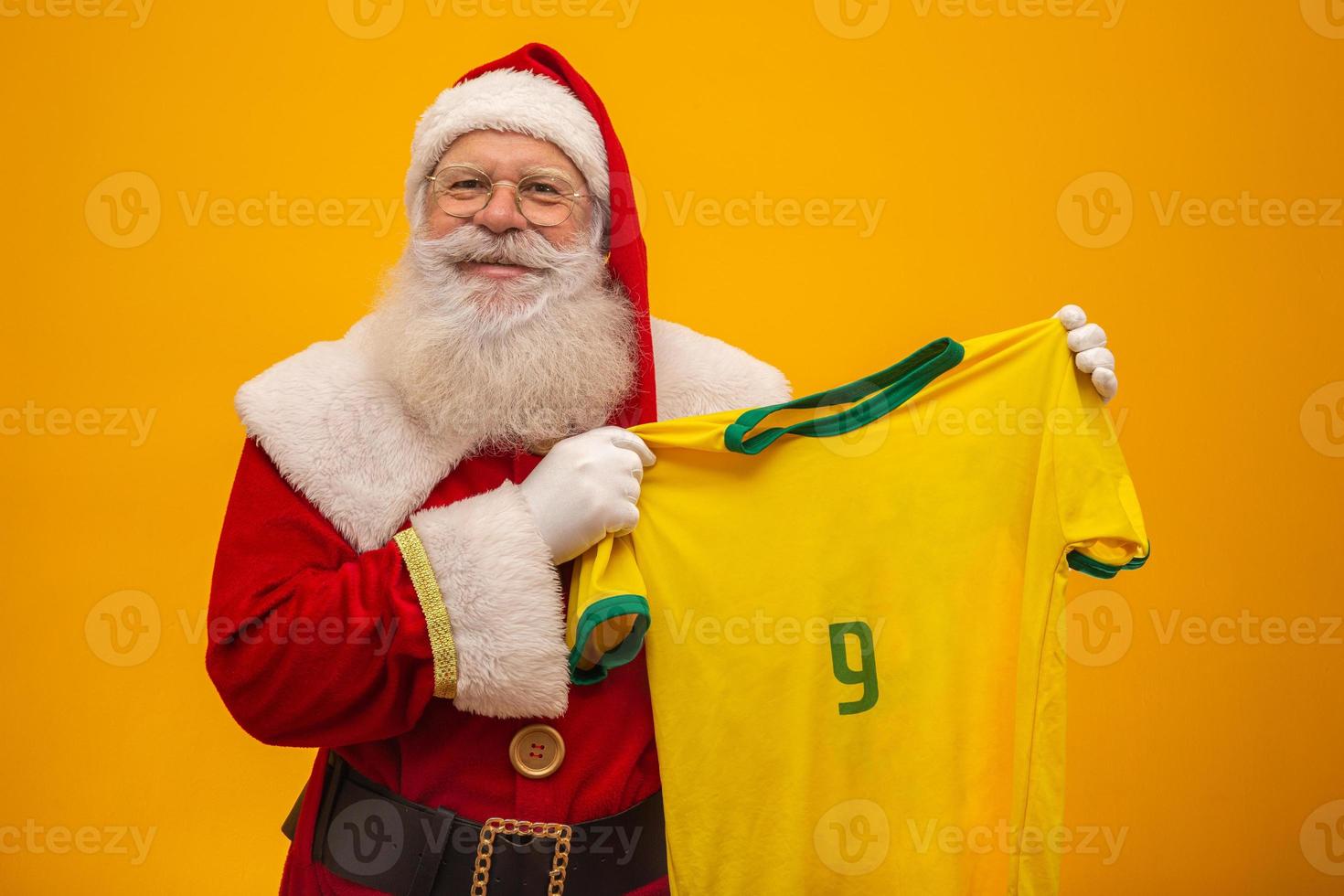 jultomten är ett fan av Brasilien. Santa Claus supporter av det brasilianska laget. idrottsmästerskap. jultomten som håller i lagets tröja. fotbollsmatch. foto